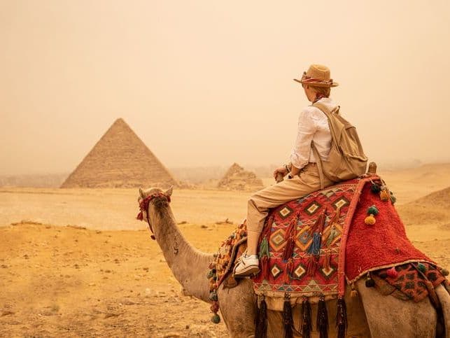 Las Pirámides de Egipto Una turista montando camello en las pirámides de Guiza