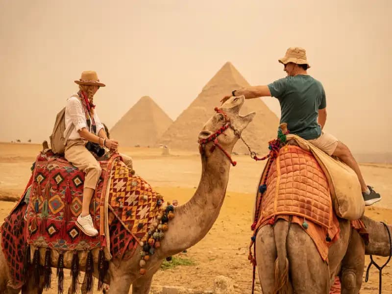 Couple Riding camels in Giza Pyramids Couple Riding camels in Giza Pyramids
