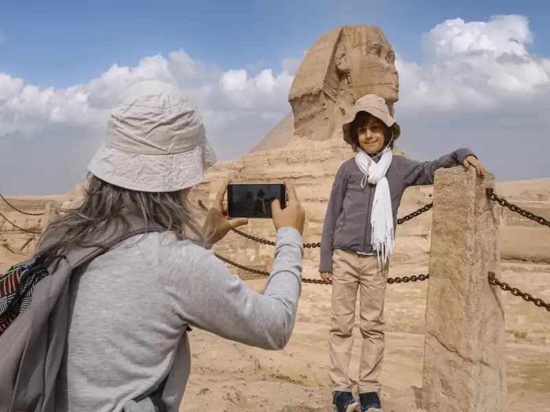 A mom taking picture of her son in Giza Pyramids A mom taking picture of her son in Giza Pyramids