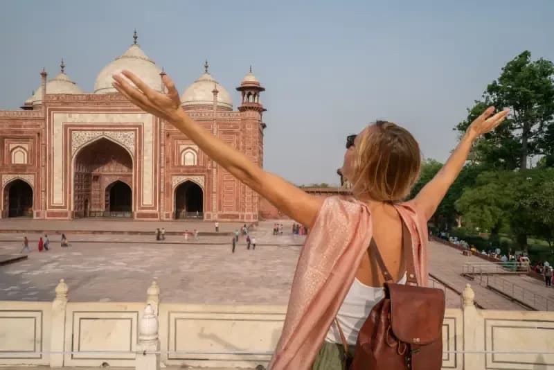 Taj Mahal, Agra, Índia mulher-de-bracos-abertos-celebrando-em-frente-a-mesquita-de-arenito-vermelho-do-complexo-do-taj-mahal-na-india