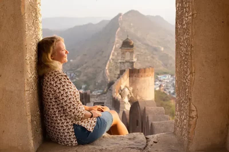 Forte de Jaigarh em Jaipur mulher-sentada-em-janela-de-pedra-contemplando-a-muralha-de-jaigarh-ao-entardecer-em-jaipur-india