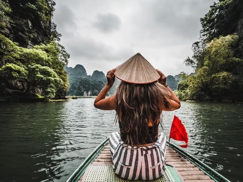 Ninh Binh, Vietnã mulher-com-chapeu-conico-vietnamita-em-barco-navegando-entre-montanhas-carsticas-em-ninh-binh-vietna
