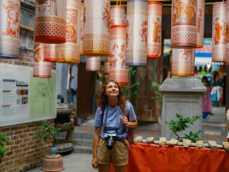 Hoi An, Vietnã turista-com-camera-observando-lanternas-decorativas-coloridas-penduradas-em-rua-tradicional-de-hoi-an-vietna