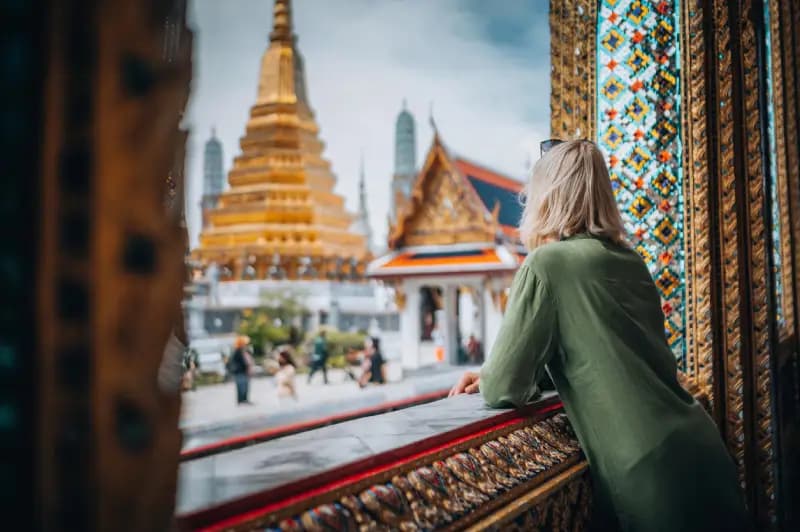Grande Palácio de Bangkok, Tailândia mulher-observando-o-pagode-dourado-do-grande-palacio-pela-janela-ornamentada-em-bangkok-tailandia