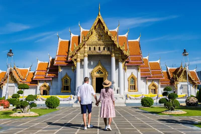 Templo de Mármore, Bangkok, Tailândia casal-de-maos-dadas-caminhando-em-direcao-ao-templo-de-marmore-wat-benchamabophit-em-bangkok-tailandia