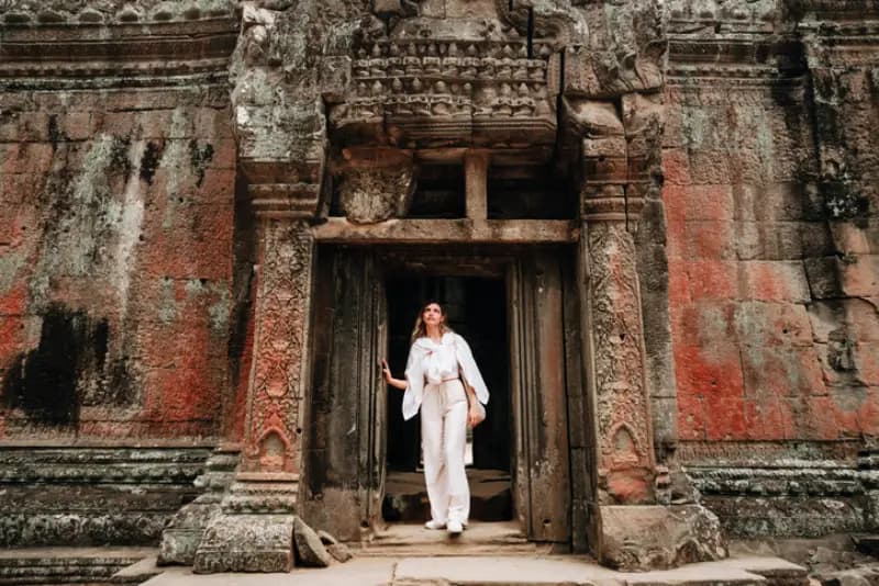 Templo de Angkor, Camboja mulher-de-branco-saindo-de-portal-de-pedra-esculpida-em-templo-antigo-de-angkor-camboja