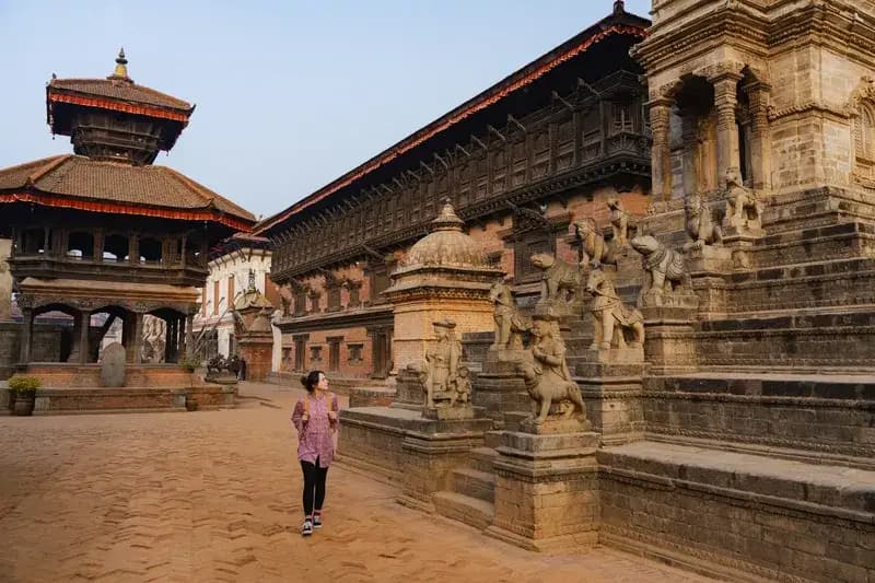 Praça Durbar de Patan mulher-caminhando-entre-templos-e-estatuas-de-leoes-esculpidas-na-praca-durbar-de-patan-no-nepal