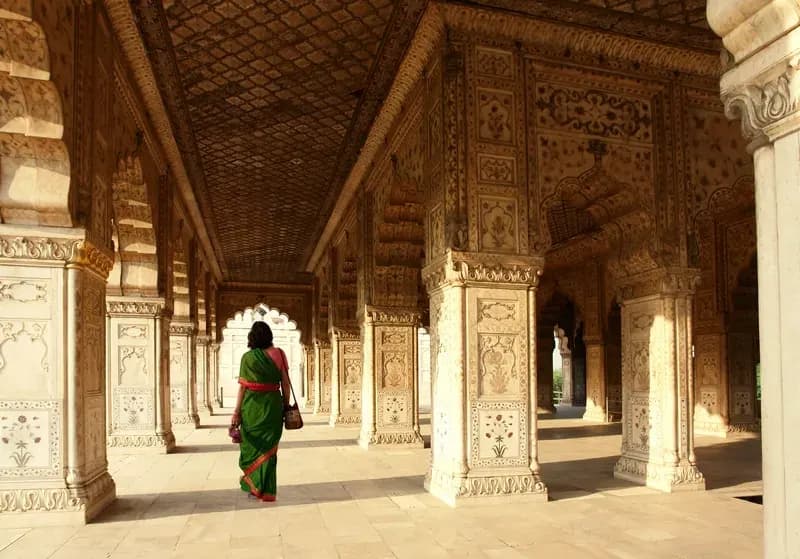 Forte de Agra mulher-usando-sari-verde-caminhando-por-um-corredor-de-colunas-esculpidas-no-forte-de-agra-india