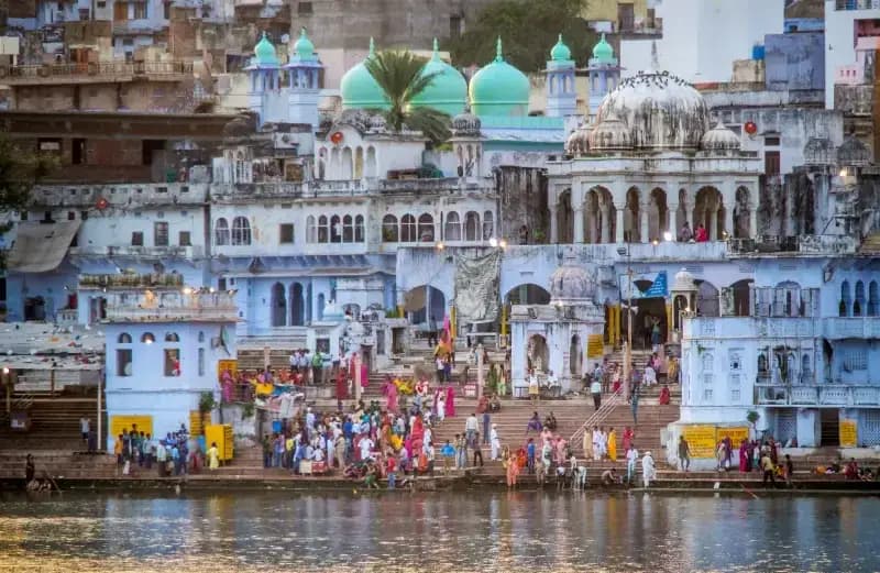 Lago de Pushkar pessoas-reunidas-nos-ghats-a-beira-do-lago-pushkar-com-predios-historicos-azuis-e-cupulas-de-templos-ao-fundo-india
