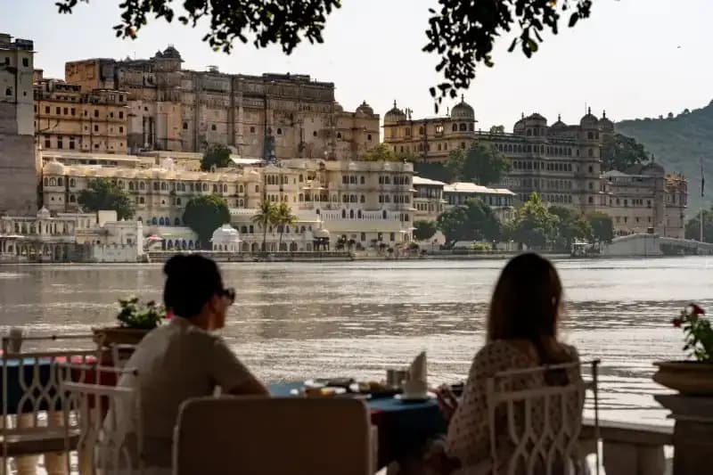 oPalácio da Cidade de Udaipur pessoas-sentadas-a-beira-do-lago-com-vista-para-o-palacio-da-cidade-de-udaipur-india