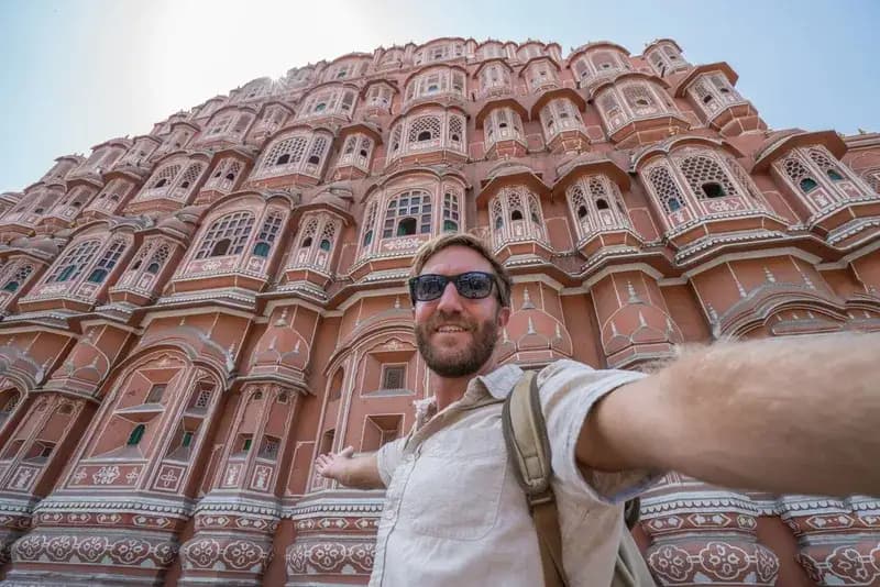 Hawa Mahal em Jaipur homem-tirando-uma-selfie-em-frente-a-fachada-rosa-ornamentada-do-hawa-mahal-em-jaipur-india