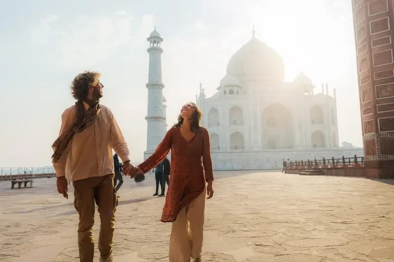 Taj Mahal casal-de-maos-dadas-caminhando-e-sorrindo-em-frente-ao-taj-mahal-ao-amanhecer-agra-india