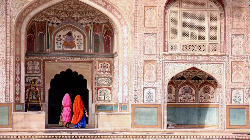 Forte Amber, Jaipur duas-mulheres-com-saris-coloridos-entrando-em-uma-passagem-arqueada-de-uma-fachada-ricamente-decorada-no-forte-amber-jaipur-india