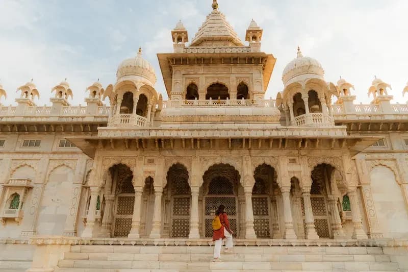 Jodhpur, Índia mulher-com-mochila-amarela-subindo-os-degraus-de-um-mausoleu-de-marmore-branco-esculpido-em-jodhpur-india
