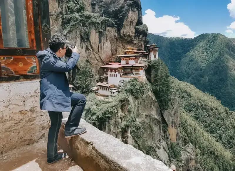 Paro, butão homem-fotografando-o-mosteiro-tigers-nest-encravado-em-um-penhasco-ingreme-em-paro-butao