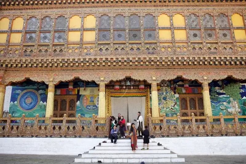 Punakha Dzong pessoas-nos-degraus-da-entrada-do-punakha-dzong-com-sua-fachada-ricamente-pintada-de-murais-coloridos-butao
