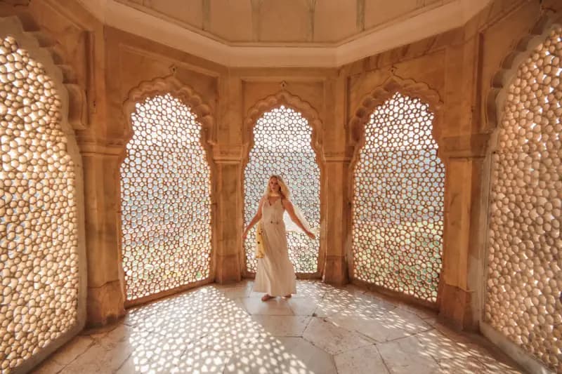 Jaipur, India woman-in-a-white-dress-standing-amid-intricately-latticed-arched-windows-inside-a-historic-palace-in-jaipur-india