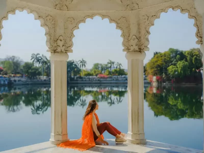 Udaipur woman-sitting-under-white-arched-pavilions-overlooking-a-calm-lake-in-udaipur-india