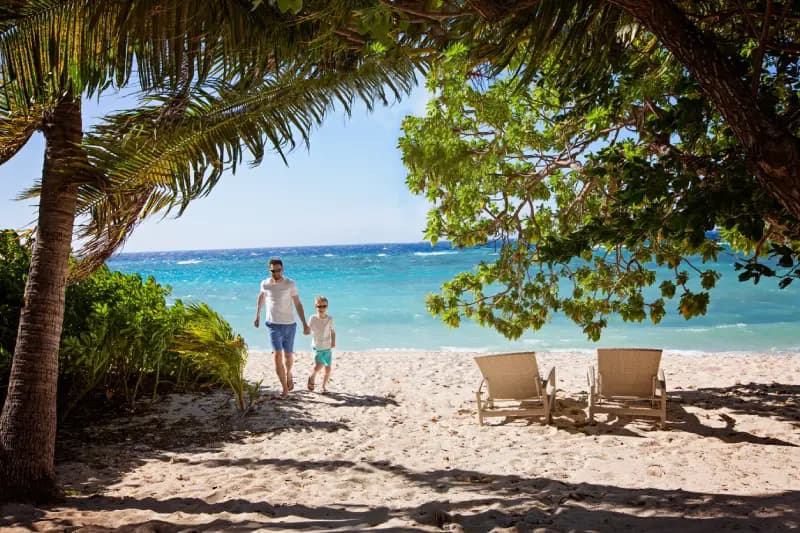 Fiji beach father-and-son-walking-together-on-a-tropical-beach-with-turquoise-water-and-palm-trees-in-fiji