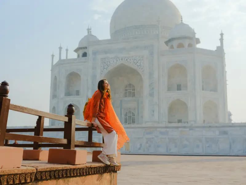 Taj Mahal in Agra woman-in-an-orange-scarf-leaning-against-a-railing-with-the-taj-mahals-marble-dome-in-the-background-agra-india