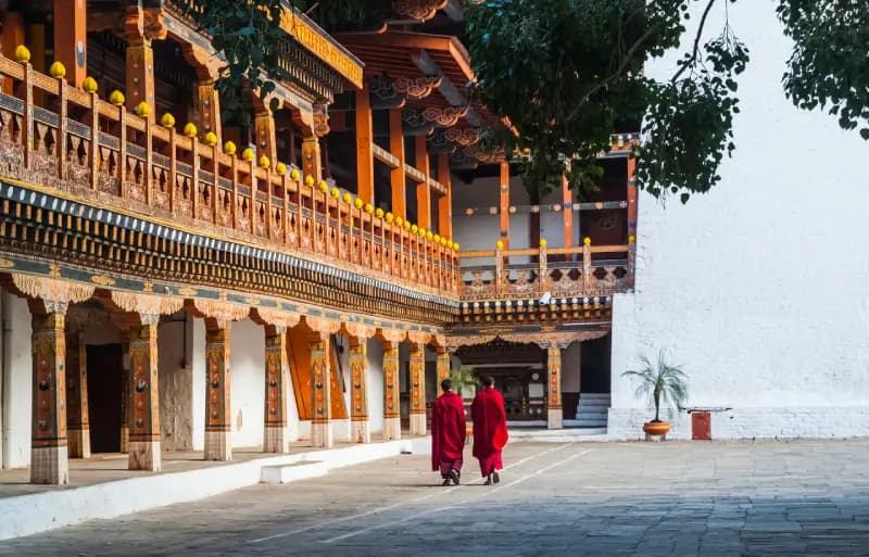 Punakha Monastery two-monks-in-red-robes-walking-through-the-courtyard-of-a-traditional-bhutanese-monastery-in-punakha-bhutan