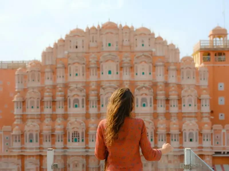 Hawa Mahal in Jaipur woman-admiring-the-honeycomb-pink-facade-of-hawa-mahal-the-palace-of-winds-in-jaipur-india