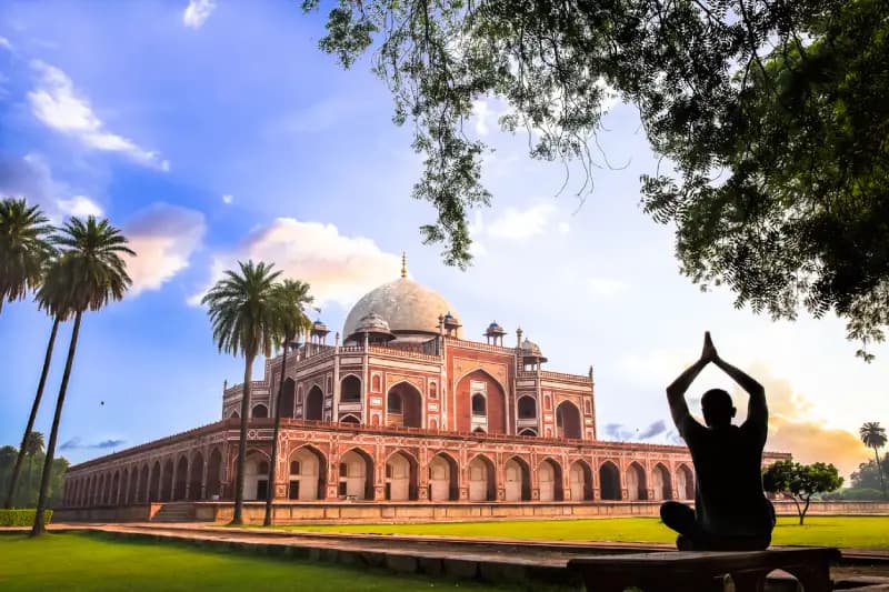 Delhi, India silhouette-of-a-person-meditating-in-yoga-pose-overlooking-humayuns-tomb-at-sunset-delhi-india