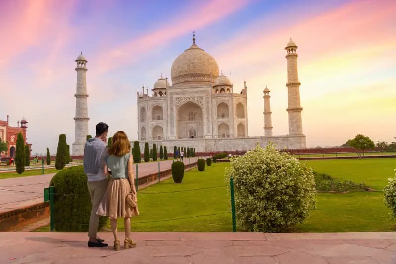 Taj Mahal at sunset couple-admiring-the-taj-mahal-under-a-colorful-sunset-sky-agra-india